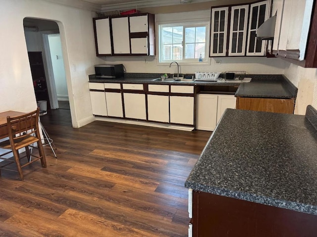 kitchen with crown molding, white cabinetry, sink, and dark wood-type flooring