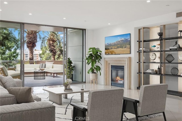 living room featuring a glass covered fireplace, visible vents, expansive windows, and recessed lighting