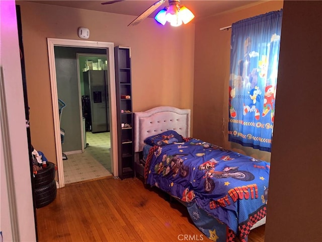 bedroom with stainless steel fridge with ice dispenser, ceiling fan, and hardwood / wood-style flooring