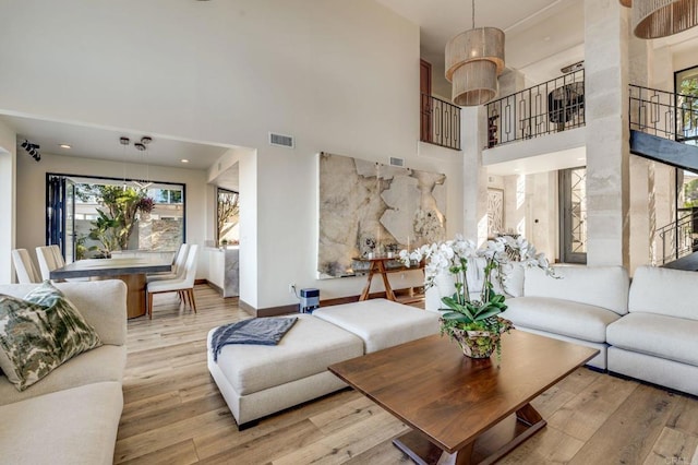 living room featuring light wood-type flooring and a towering ceiling