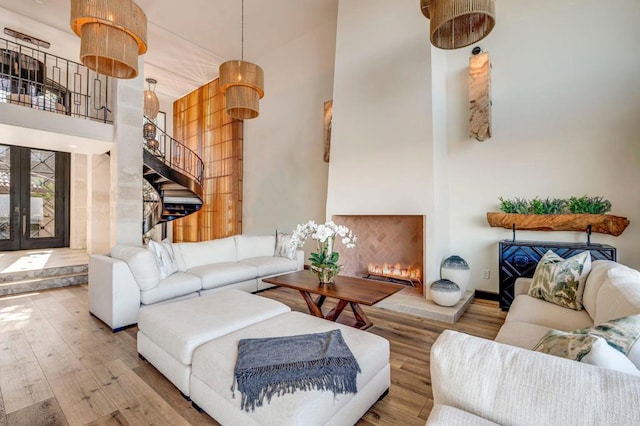 living room with a fireplace, hardwood / wood-style flooring, a towering ceiling, and french doors