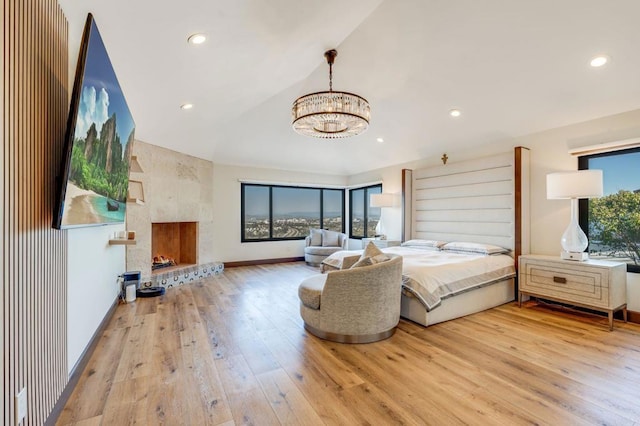 bedroom featuring light hardwood / wood-style floors, multiple windows, vaulted ceiling, and a fireplace