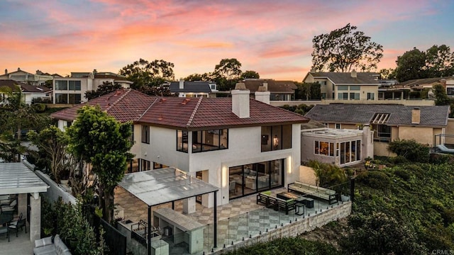 back house at dusk featuring a patio area