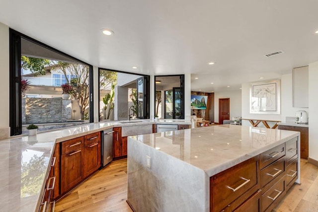 kitchen featuring light hardwood / wood-style floors, light stone countertops, sink, and a kitchen island