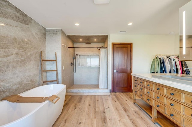 bathroom with hardwood / wood-style floors, plus walk in shower, and vanity