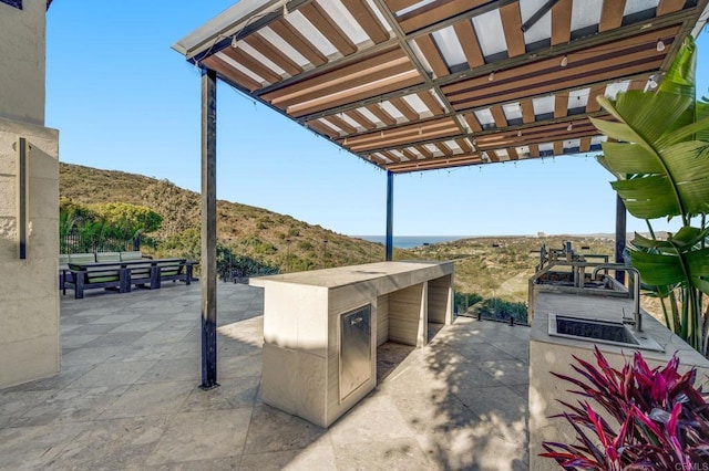 view of patio featuring a mountain view, an outdoor kitchen, and a pergola