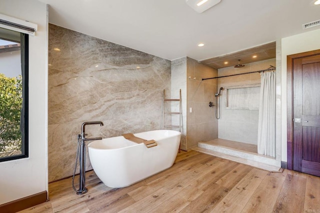 bathroom featuring tile walls, hardwood / wood-style floors, and plus walk in shower