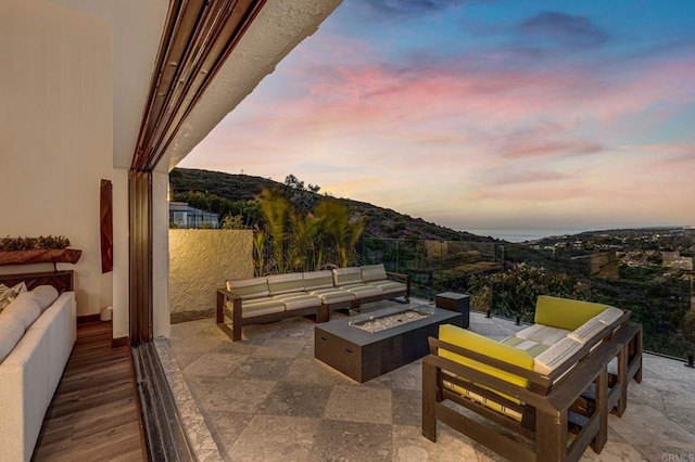 patio terrace at dusk with a mountain view and an outdoor living space with a fire pit