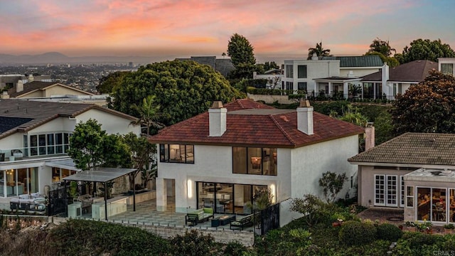 back house at dusk featuring a patio and french doors