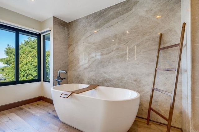 bathroom featuring a tub, tile walls, and wood-type flooring