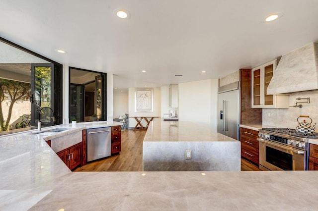 kitchen featuring custom exhaust hood, sink, tasteful backsplash, a kitchen island, and stainless steel appliances