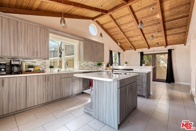 kitchen featuring tasteful backsplash, a kitchen island with sink, sink, and decorative light fixtures