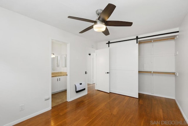 unfurnished bedroom with ceiling fan, hardwood / wood-style floors, ensuite bathroom, and a closet