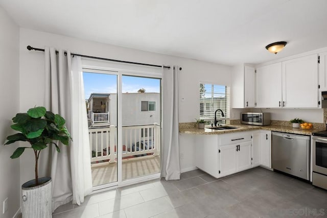 kitchen featuring sink, light tile patterned flooring, white cabinetry, appliances with stainless steel finishes, and light stone counters