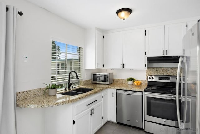 kitchen featuring white cabinetry, stainless steel appliances, light tile patterned flooring, light stone counters, and sink