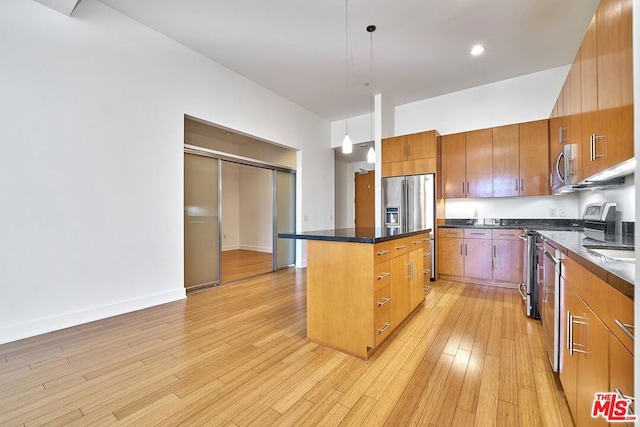 kitchen with appliances with stainless steel finishes, a kitchen island, pendant lighting, and light hardwood / wood-style floors