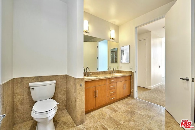 bathroom with vanity, tile walls, and toilet