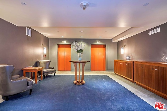 living area featuring elevator and light colored carpet