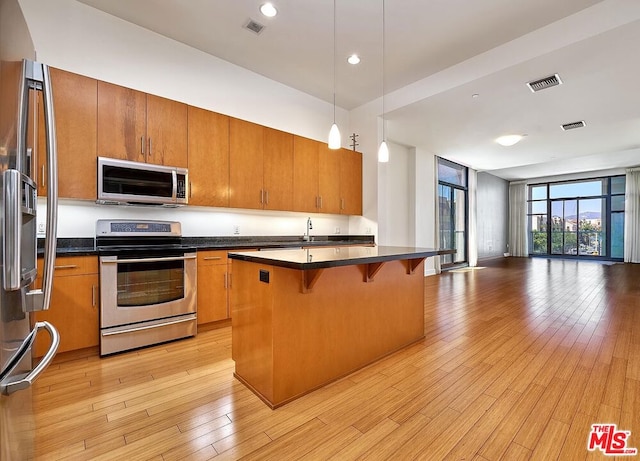 kitchen with pendant lighting, a center island, a kitchen breakfast bar, light wood-type flooring, and stainless steel appliances