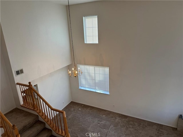 stairway featuring a notable chandelier, a high ceiling, and carpet flooring