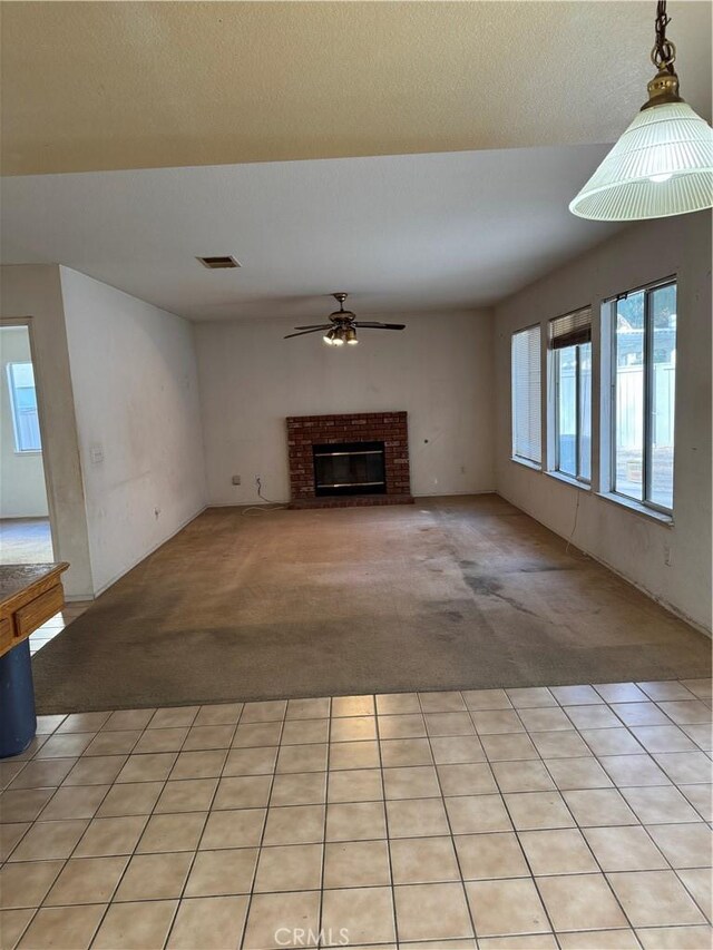 unfurnished living room with light carpet, ceiling fan, and a brick fireplace