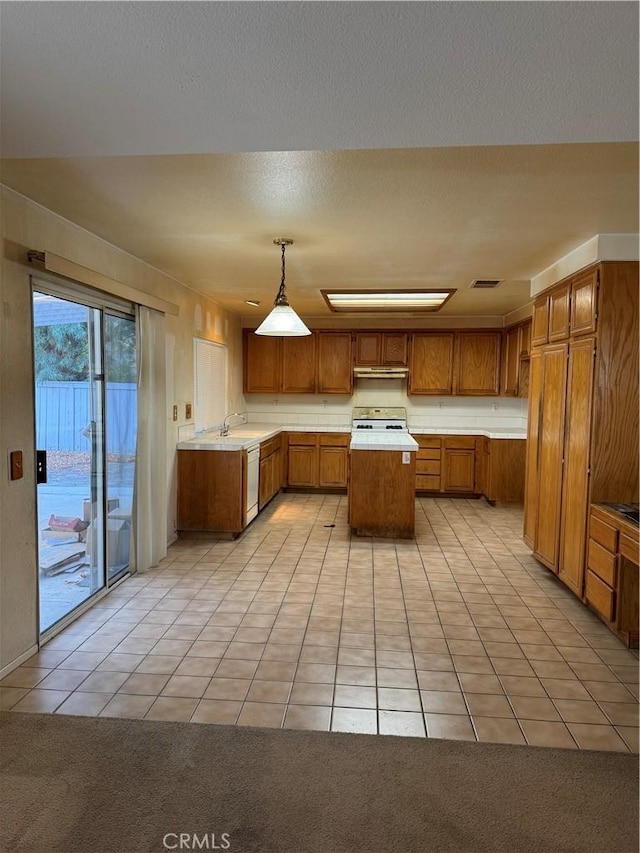 kitchen with light tile patterned floors, stove, white dishwasher, pendant lighting, and a center island