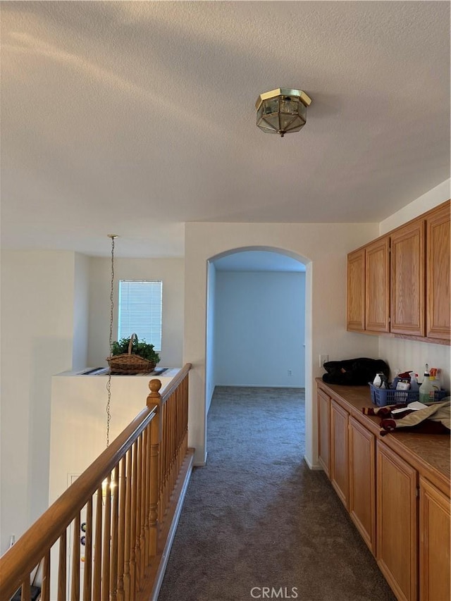 interior space with a textured ceiling and dark carpet