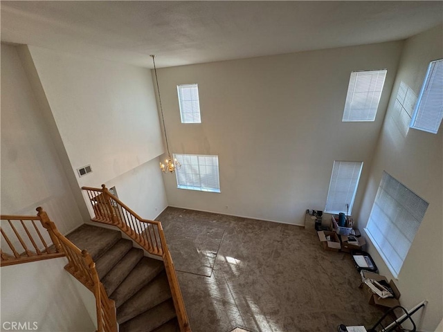 unfurnished living room with carpet, a chandelier, and a towering ceiling