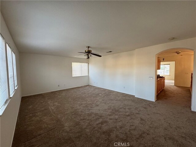 empty room with ceiling fan and dark carpet