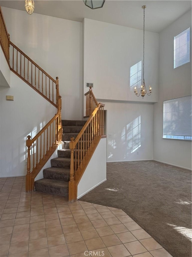 stairs featuring carpet flooring, a chandelier, and a towering ceiling