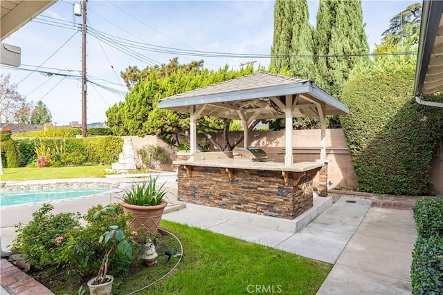 view of patio with exterior kitchen, a gazebo, grilling area, a fenced in pool, and an outdoor bar