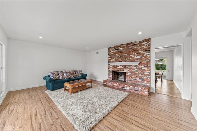 living room with a brick fireplace and light wood-type flooring