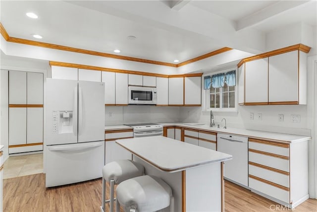 kitchen with a center island, white appliances, light wood-type flooring, white cabinetry, and a breakfast bar area