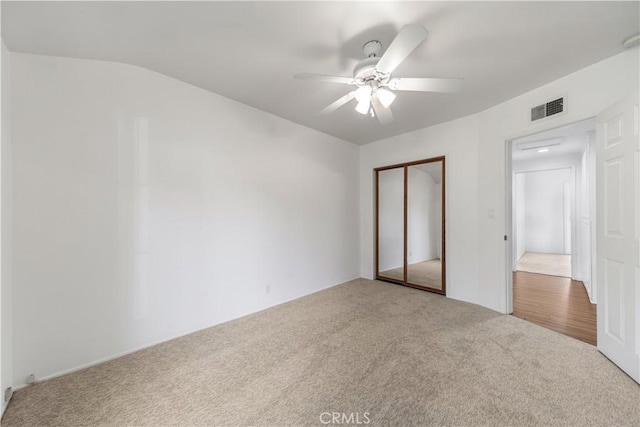 unfurnished bedroom featuring carpet, a closet, ceiling fan, and lofted ceiling