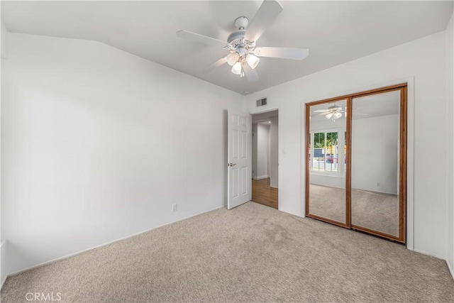 unfurnished bedroom featuring carpet flooring, a closet, vaulted ceiling, and ceiling fan