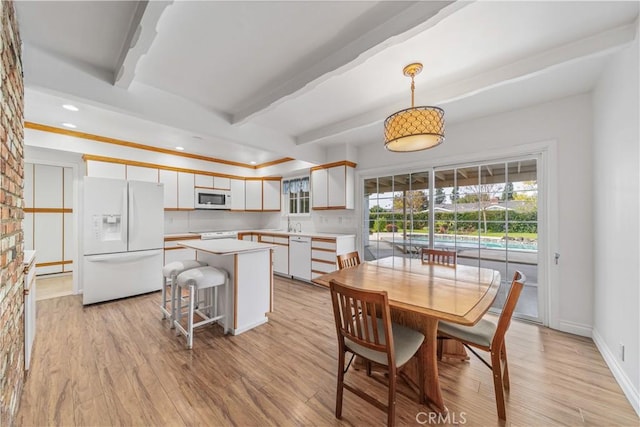 dining space with beam ceiling and light wood-type flooring