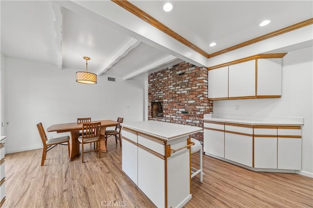 kitchen with a kitchen island, light hardwood / wood-style flooring, crown molding, pendant lighting, and white cabinets