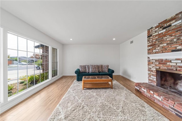 sitting room with hardwood / wood-style flooring, a brick fireplace, and a healthy amount of sunlight