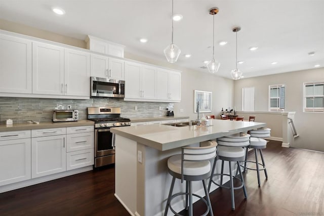 kitchen featuring white cabinets, stainless steel appliances, and a kitchen island with sink