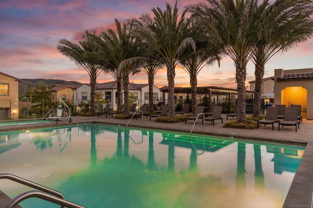 pool at dusk featuring a patio area