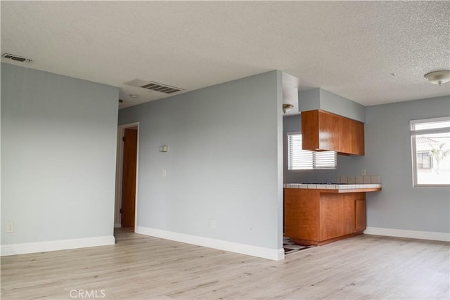 kitchen featuring tile countertops, a textured ceiling, and light hardwood / wood-style flooring