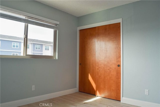 unfurnished bedroom featuring a closet, light hardwood / wood-style flooring, and a textured ceiling