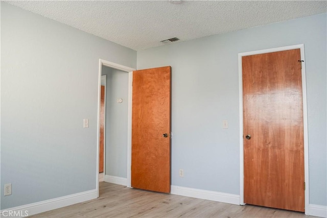 unfurnished bedroom featuring light hardwood / wood-style flooring and a textured ceiling