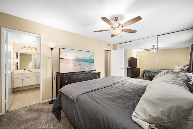 carpeted bedroom with ceiling fan, sink, ensuite bathroom, and a closet