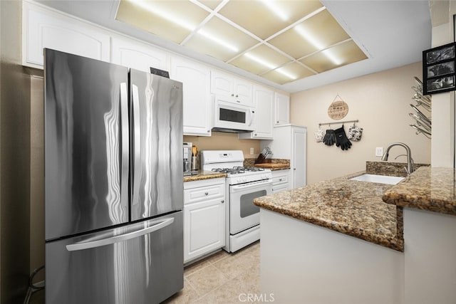 kitchen with white cabinetry, white appliances, sink, and dark stone counters