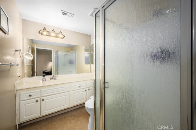 bathroom featuring tile patterned floors, vanity, a shower with shower door, and toilet