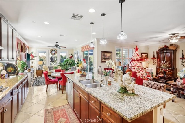 kitchen with crown molding, sink, an island with sink, and light tile patterned floors