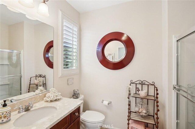 bathroom with toilet, plenty of natural light, vanity, and walk in shower