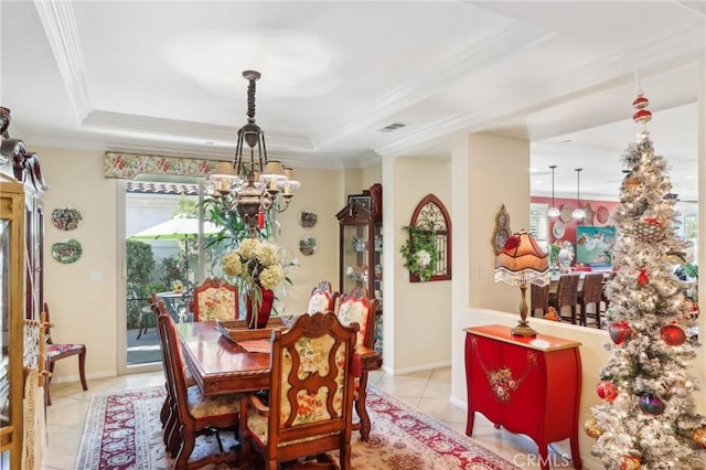 tiled dining area featuring a raised ceiling, crown molding, and a chandelier