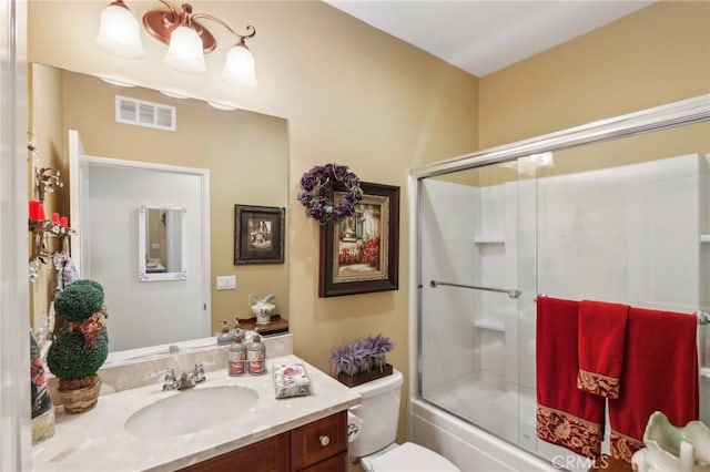 full bathroom featuring toilet, combined bath / shower with glass door, and vanity